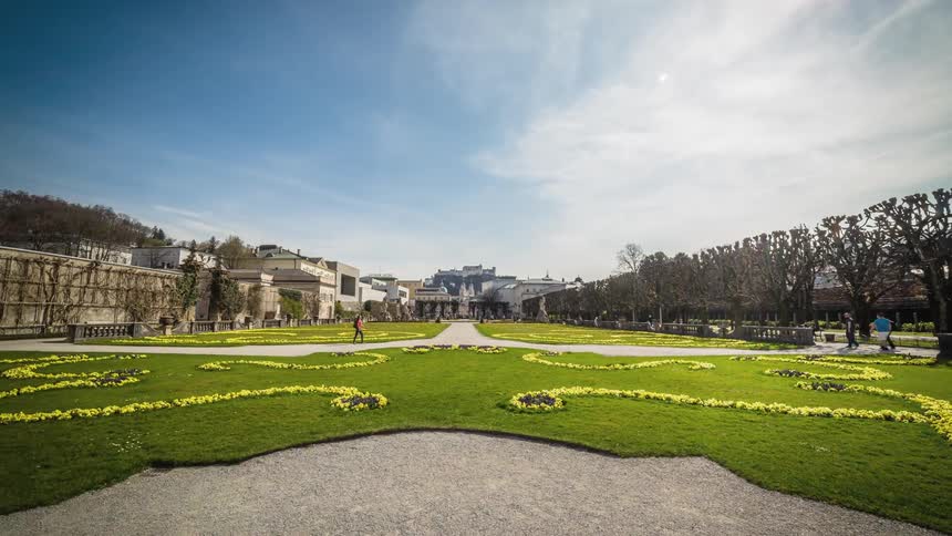 People walk through and around manicured gardens and lawns