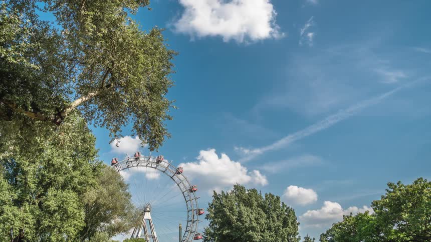 A ferris wheel turns as clouds grow and change