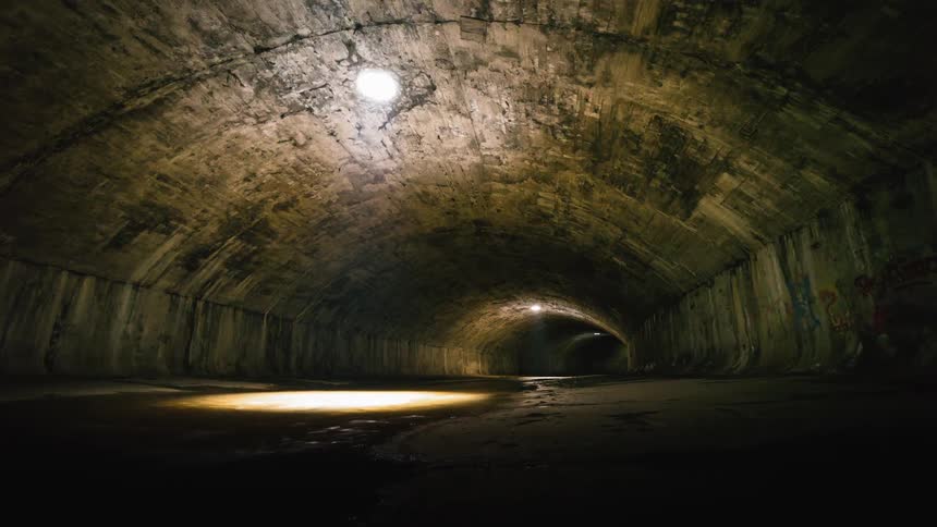 A light turns on at the end of a dark dirty tunnel