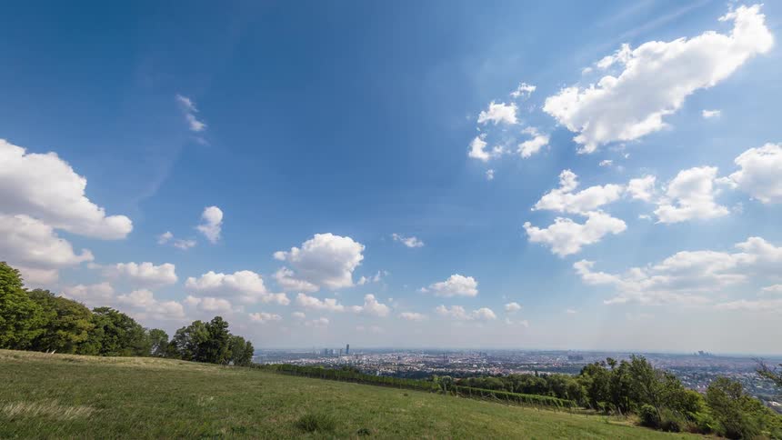 Clouds float over a grassy hillside on a summer day