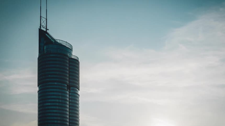 Clouds by a tall skyscraper