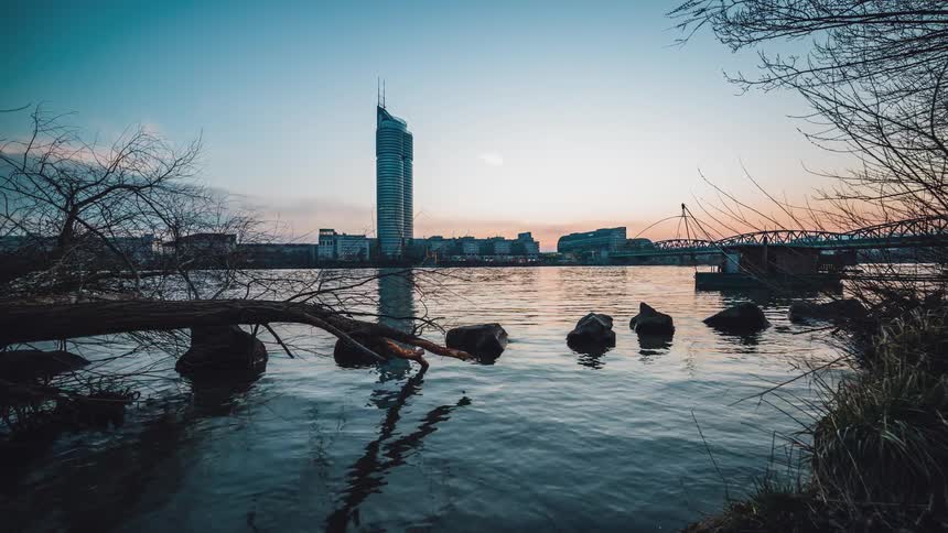 The sun rising and falling on a waterway outside of a metropolis