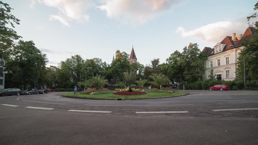 Traffic moving around a roundabout near a large building