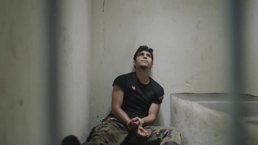 A man is a prisoner while handcuffed in a jail cell