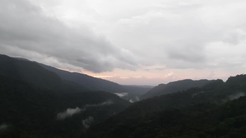 Sun rising over mountain and valleys under cloudy sky
