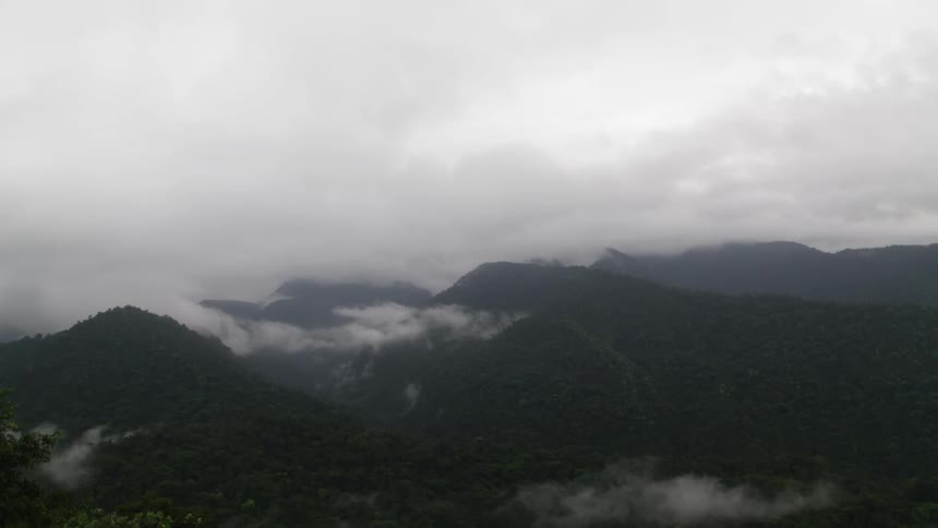 Clouds hover over a forested mountain range