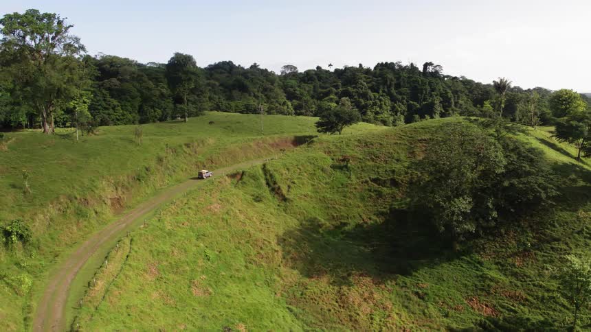 A single car drives along a road through the hillside