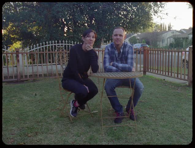 A couple sit in their yard talking to each other