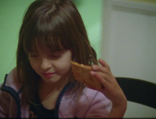 A family at the dinner table having a dominoes pizza as the daughter talks before reaching to the table