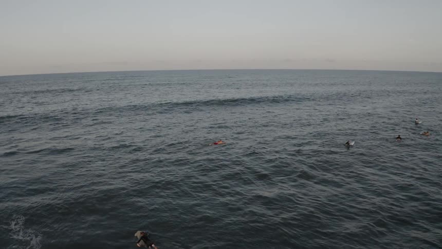 Surfers lying on surfboard paddle out to sea