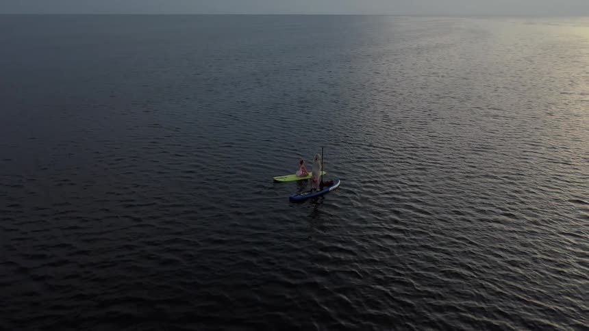 Two people are on surfboards in the middle of a calm ocean