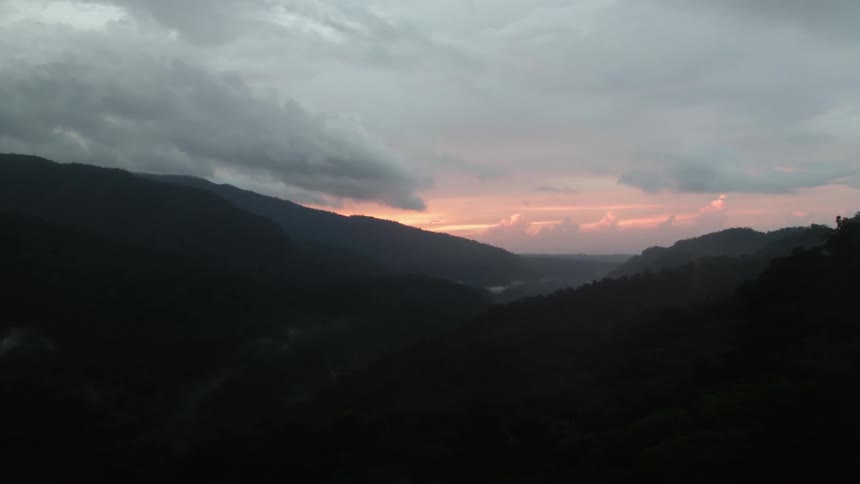 The sun rests behind a mountain range