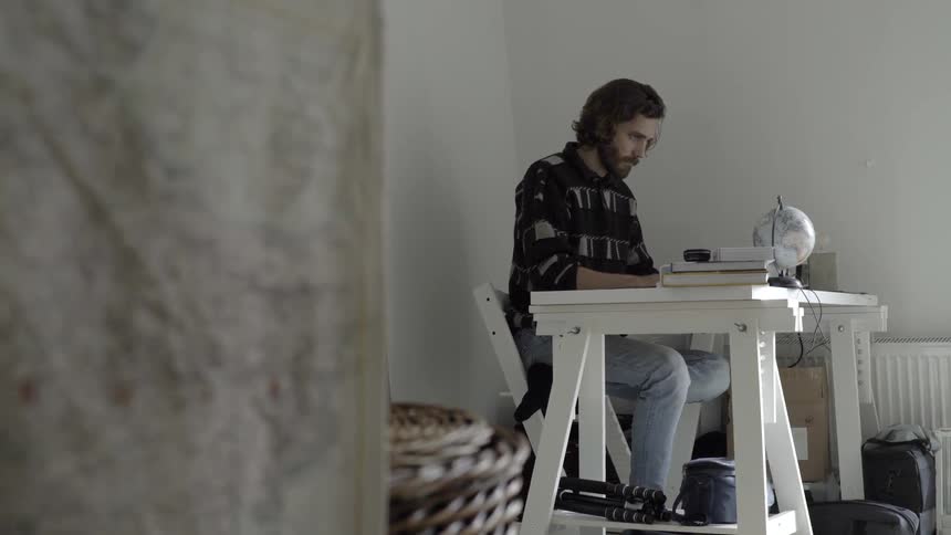 A man is sitting at a desk indoors looking down