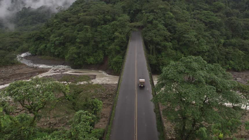 A vehicle crosses a bridge into the woods