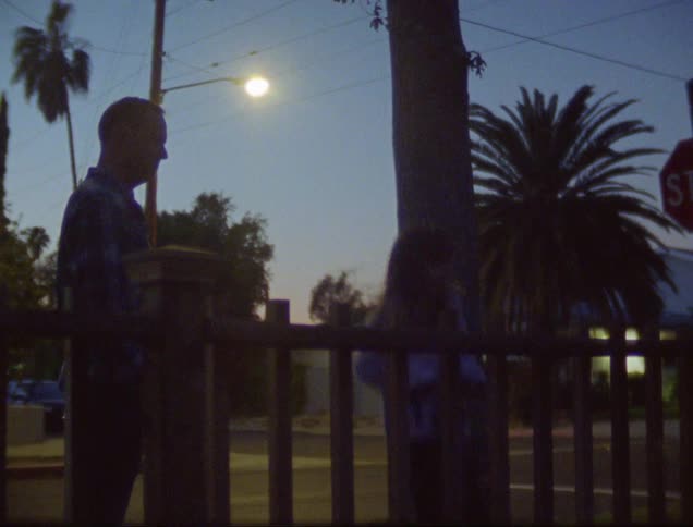 A young girl jumps up and down on a pogo stick as her father watches at sunset