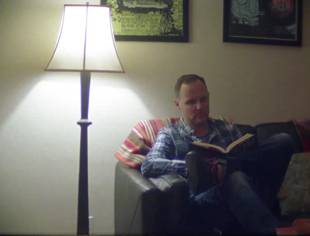 Man sits on couch and reads a book
