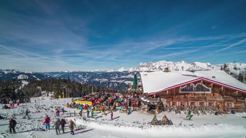 People moving about around a ski lodge on a sunny winter day