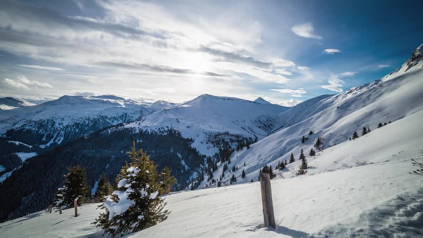 Mountains covered with snow and clouds above time lapse
