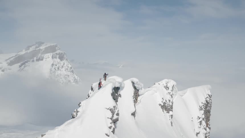 Skiers hiking to the top of a snow capped summit in the mountains