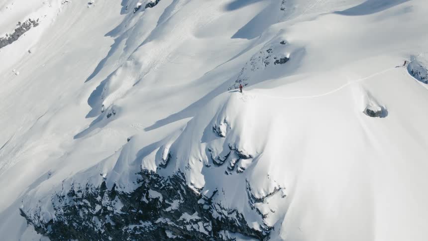 A top a mountain a skier stands in the snow on a mountain cliff