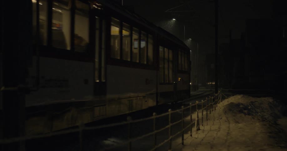 A train at night time moving through the snow