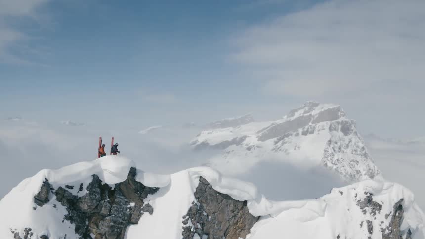 Two people stand on top of a snowy mountain