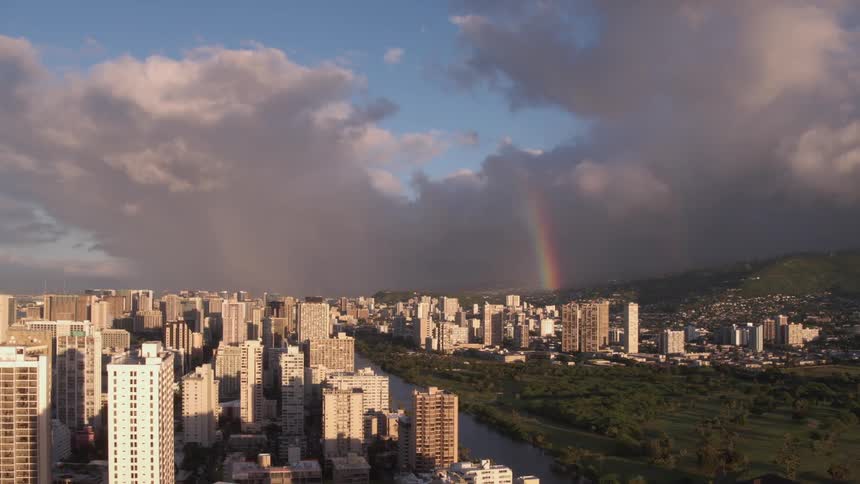 A rainbow stretching into the sky over a large city