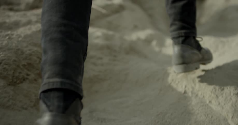 A man walks up a sandy trail