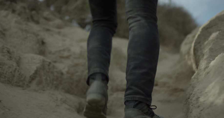 A man walking through sand dunes