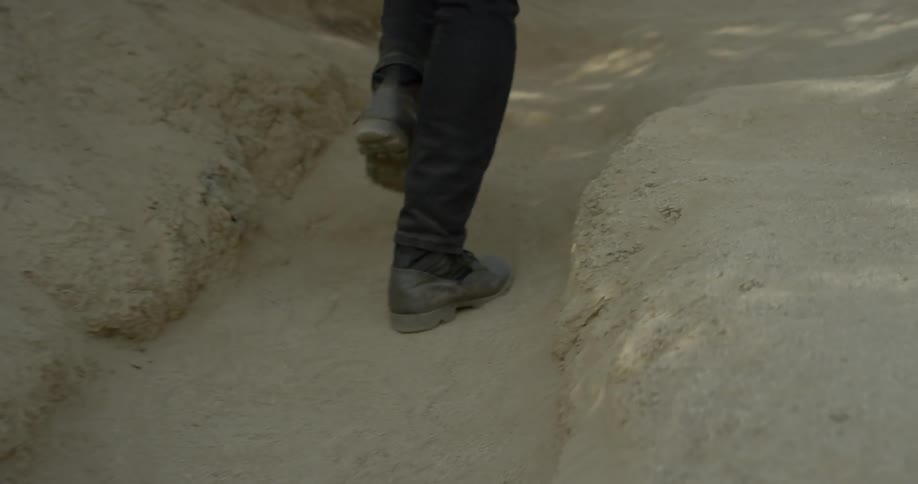 Man hurries up dirt path on hill side