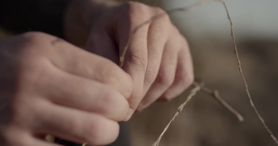 Someone slides branch pieces through their fingers