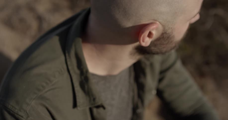 A man squints his eyes while sitting outside on a sunny day