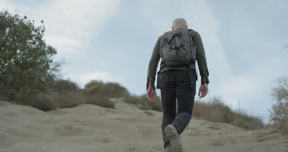 Man walks up a steep sand hill