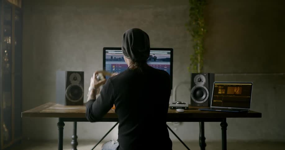 Person sits at table listening to music on computer