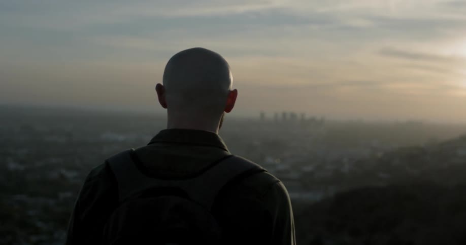 Man walks on hills above city in early morning