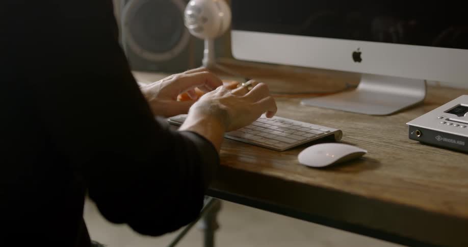 A person types on a keyboard while using a computer at a desk