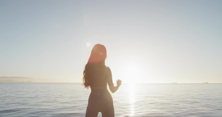 A woman stretches next to the water