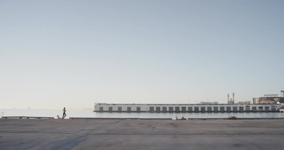A woman jogs down a long empty pier