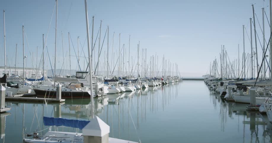 Early morning at the marina with sailboats docked and water smooth as glass