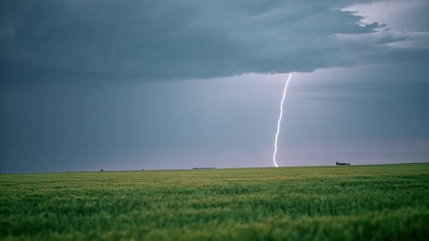 Lightning that is flashing over a grassy field