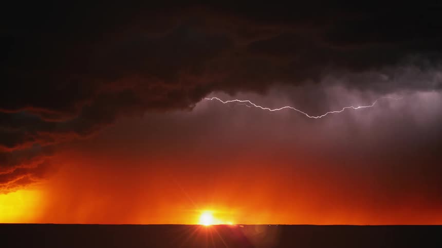 Rain falls and lightning flares as the sun sets