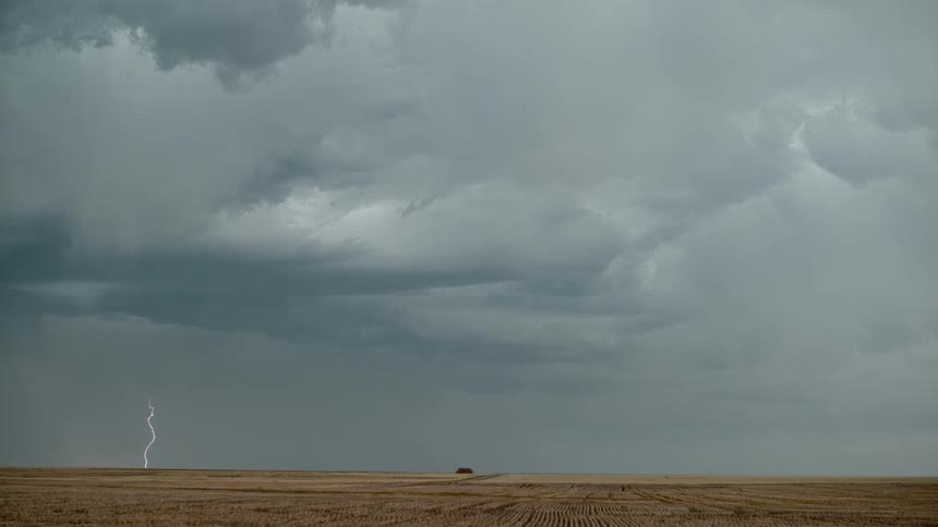 A lightning storm hovers over farmland