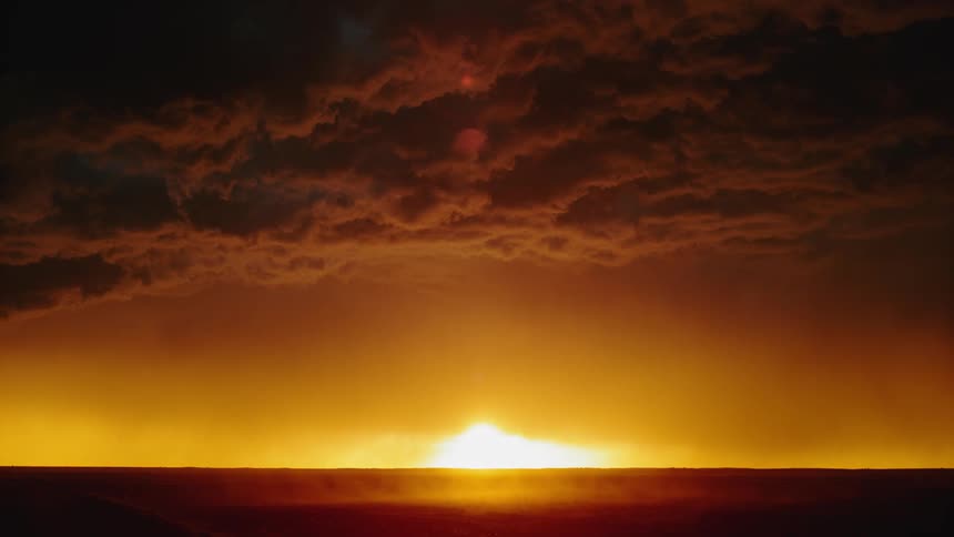 Clouds above the sun rising over the horizon