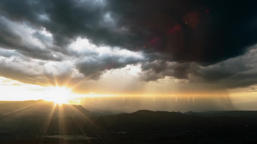 Sun shines beneath the sky covered with heavy clouds