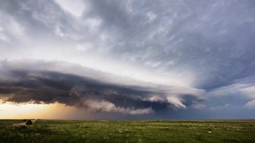 Timelapse of storm clouds forming over a highway and grassland area