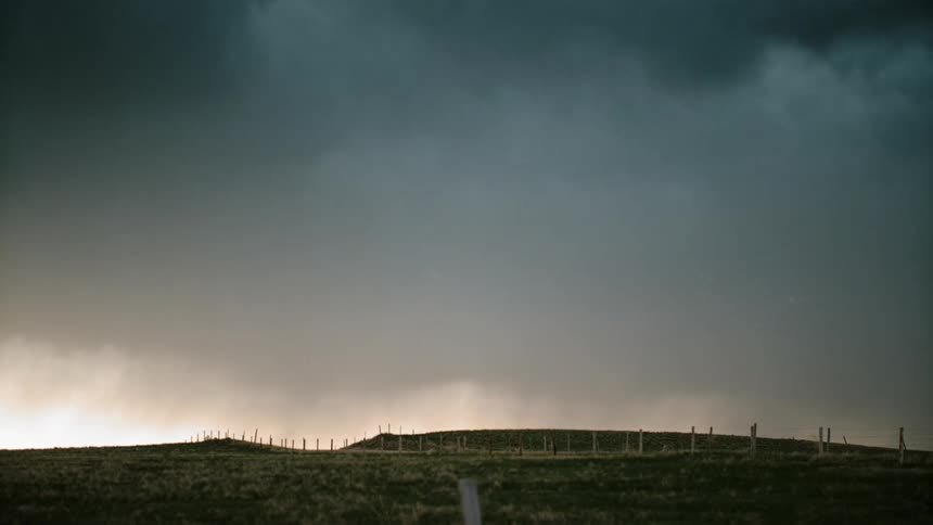 Rain clouds with lightning loom over a rural area