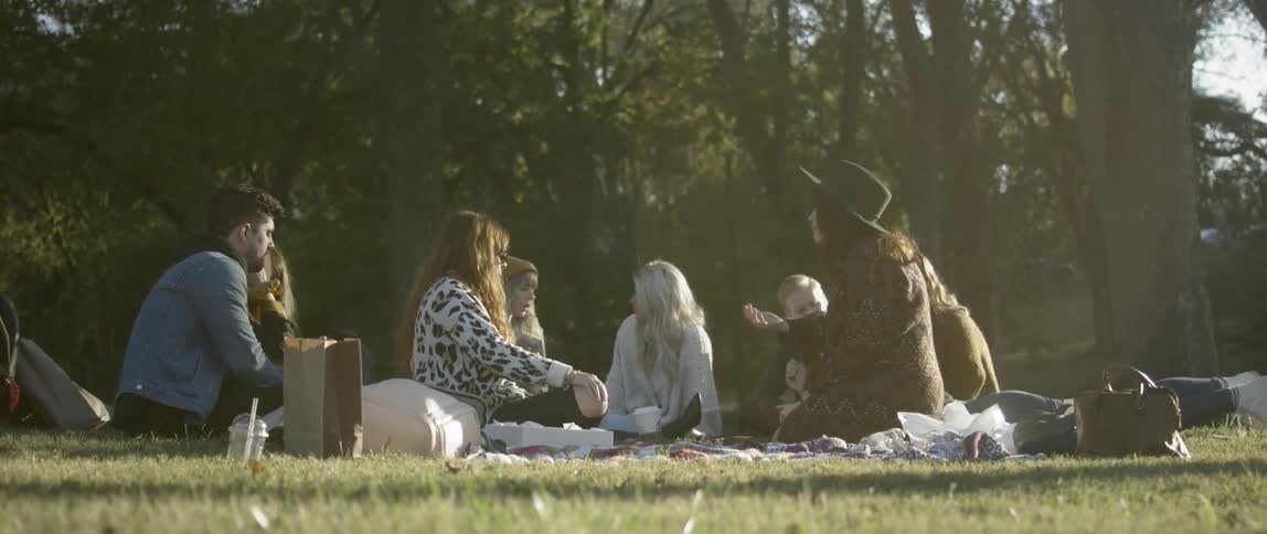 A group of people talking while having a picnic outdoors on a sunny day