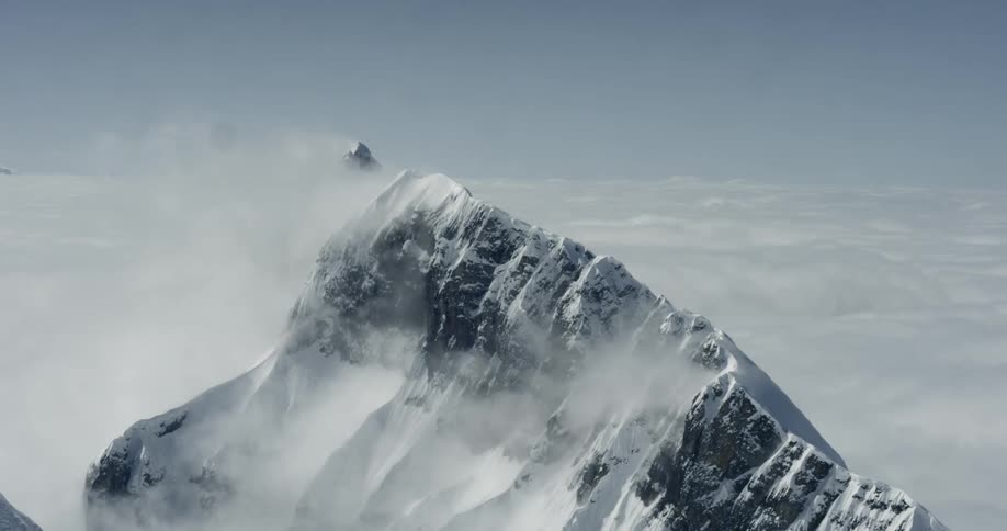 The peak of a mountain pokes between clouds