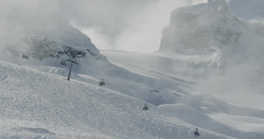 Ski lift cars make their way up and down a mountain slope