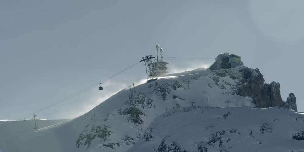 Overhead cable car nears top of snowy mountain